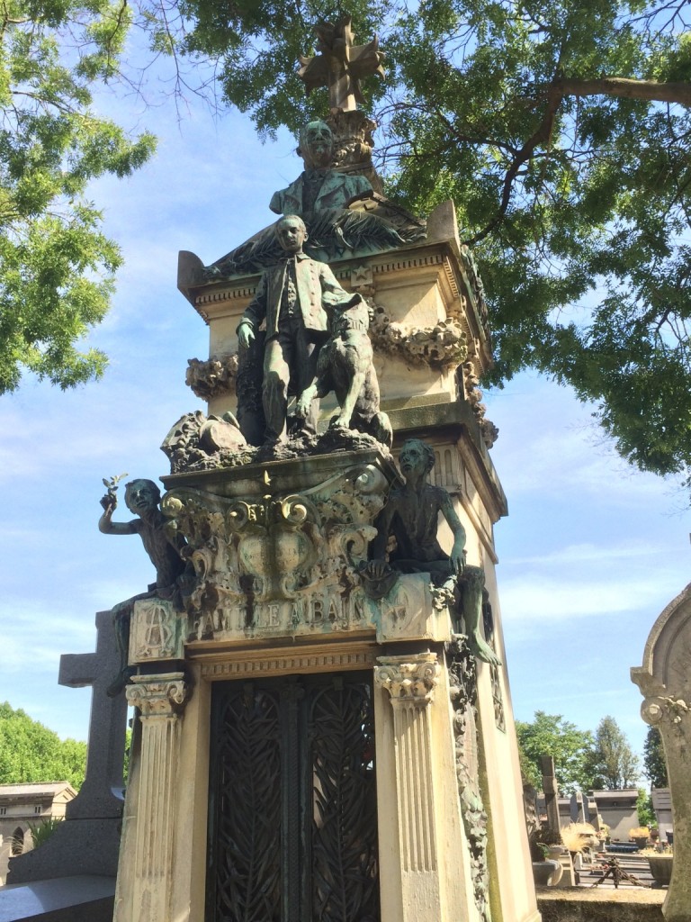 multi-tier grave monument with man, children, and dogs