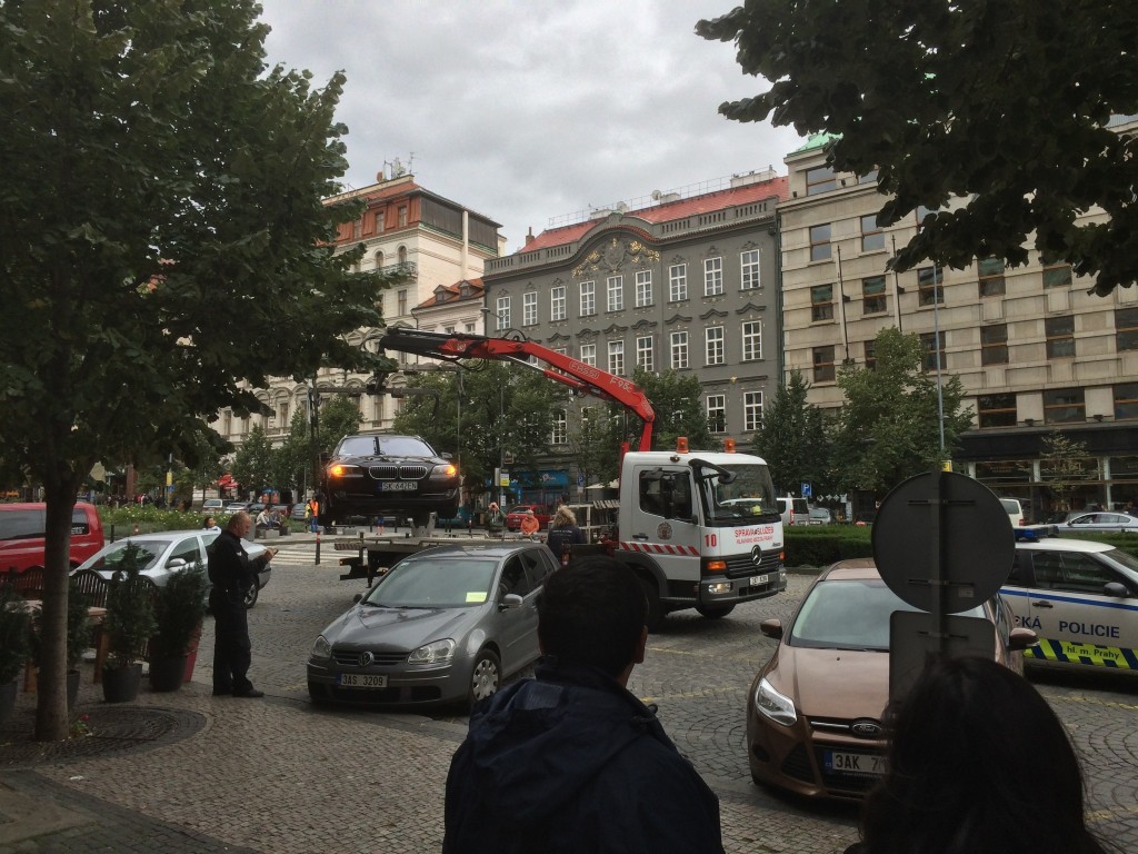 Car being towed by vertical lift via crane in Prague